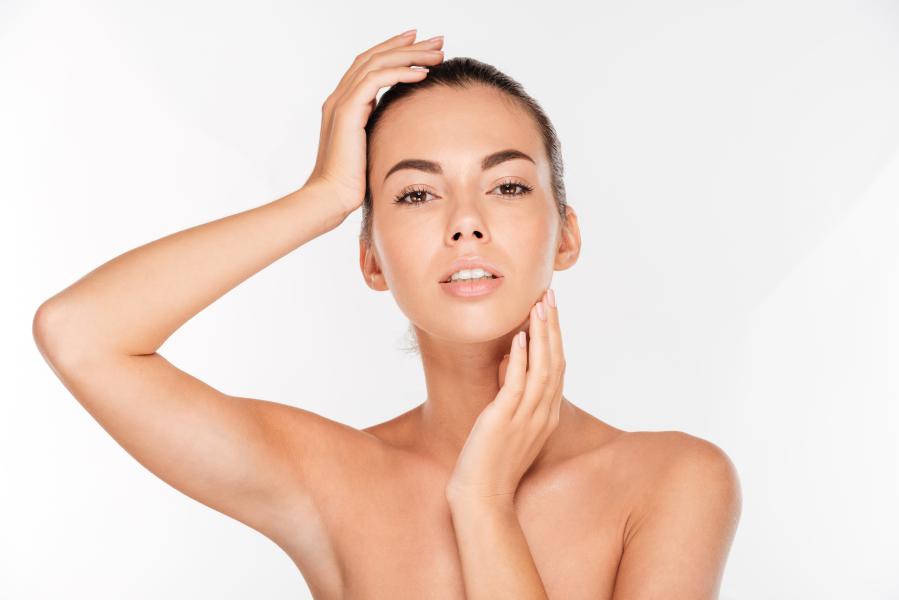 Woman modeling her face and neck after receiving non-surgical dermal fillers and injectables.